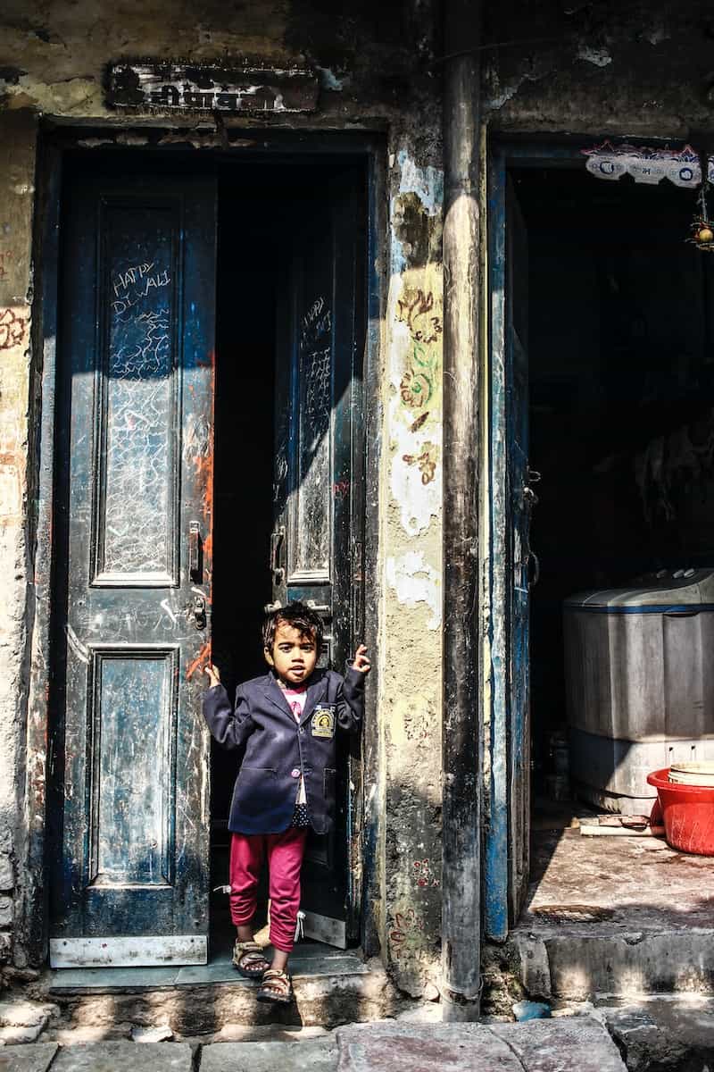 boy in black and red jacket standing in front of blue and white wooden door
