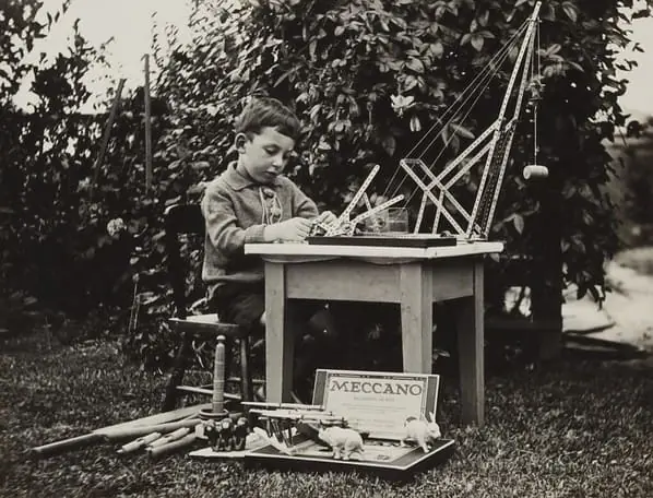 boy sitting on chair playing with meccano